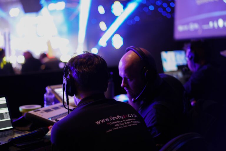 Image of 3 firefly employees backstage at an event working with different equipment