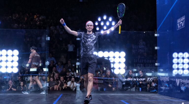 Photo of a squash player celebrating with a crowd watching